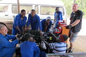 Mercy Tech volunteer instructors Todd Green (left) and Ed Hyslip (right) dismantle a diesel generator with Mozambican students.