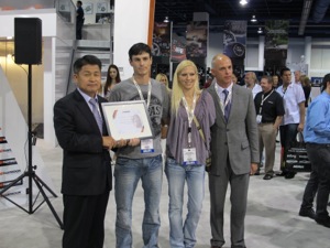 derrelle and amanda ruschel (center) accept recognition for hankook heroes from hankook tire america corp.s soo il lee, president and ceo (left), and shawn denlein, senior vice president of sales and marketing. 
