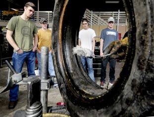 Students in Sentinel High Schools automotive shop watch as Gary Bakke applies rubber lube to the edges of a tire as he demonstrates how to both take a tire off of a wheel and mount it back on. (Photo By Kurt Wilson, The Missoulian)